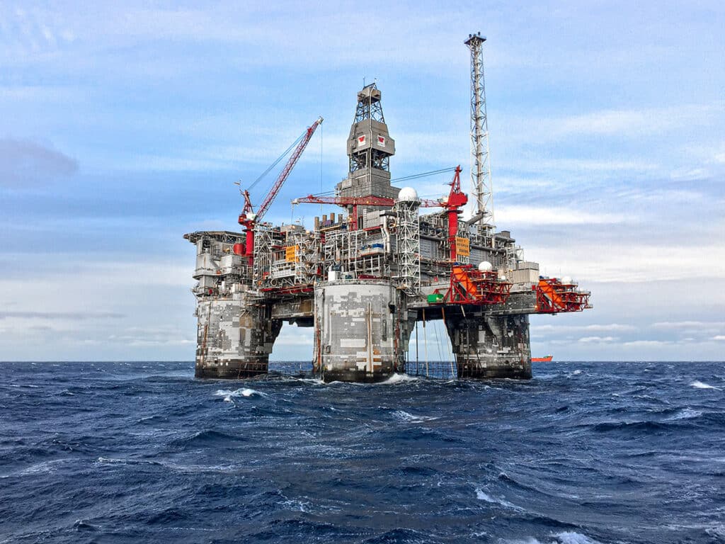 A large oil rig in a rough ocean that has been serviced by Corrocoat